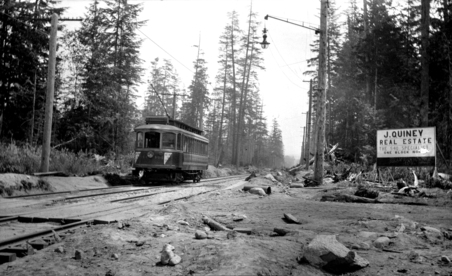 1909 年有軌電車擴展至 Kitsilano 來幫助開發，圖中的位置是當時的 4th Avenue West 及 Waterloo Street 交界，圖右還有一個 J. Quiney Real Estate 的地產經紀廣告牌。(City of Vancouver Archives)