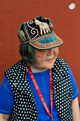 原藉江西的 Ms. Chen 移居 Oakland 前曾住過大陸與台灣，能操英語及多種中國方言。她的威風泰國繡花帽跟上衣顏色圖案非常配襯。