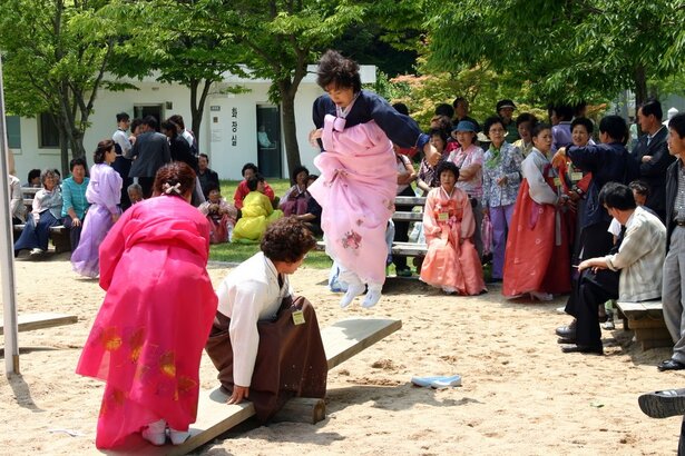 韓國也會慶祝端午節，但不是紀念屈原，而是一個祭天和驅瘟的節日。人們會在這天吃車輪餅糕，女子會在這天跳板舞（如圖所示）、盪鞦韆，並用菖蒲水洗頭。(Photo from Wikipedia)