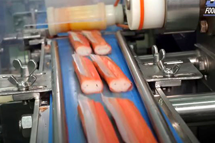 之後在魚漿中加入橘紅色染料，再使用塑型機器切絲、捲起、切割，最後進行真空包裝並冷凍。