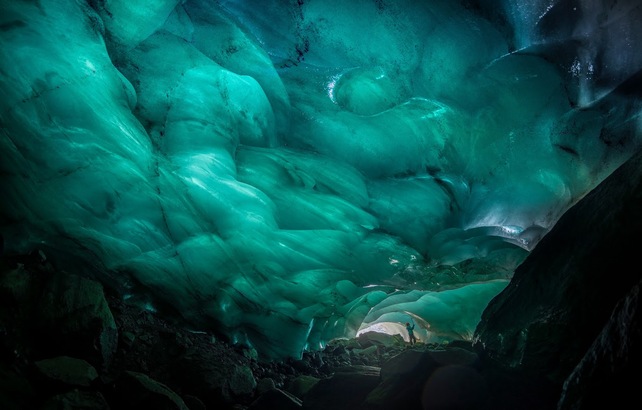 在冰洞內，太陽光經過厚厚的冰層透射下來，變成一片藍綠色。