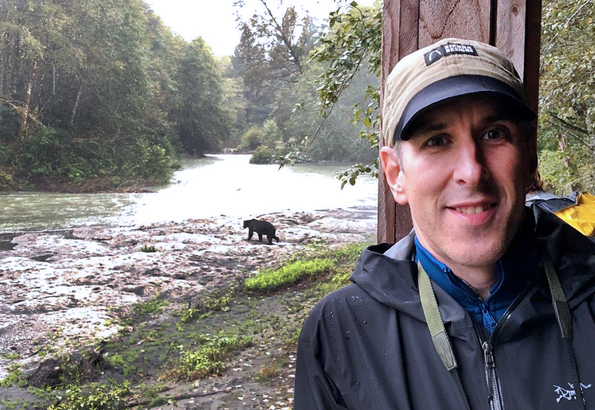 Klahoose Wilderness Resort 旅遊經理 Chris Tait，和遠處的大灰熊合攝。