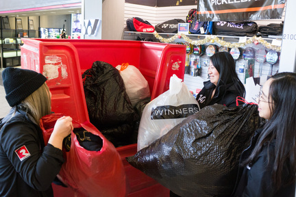 Radio Idol Monqiue（左）、Spencer (右) 和 Tracy (中) 把一袋袋衣物放進救世軍的回收車內。
